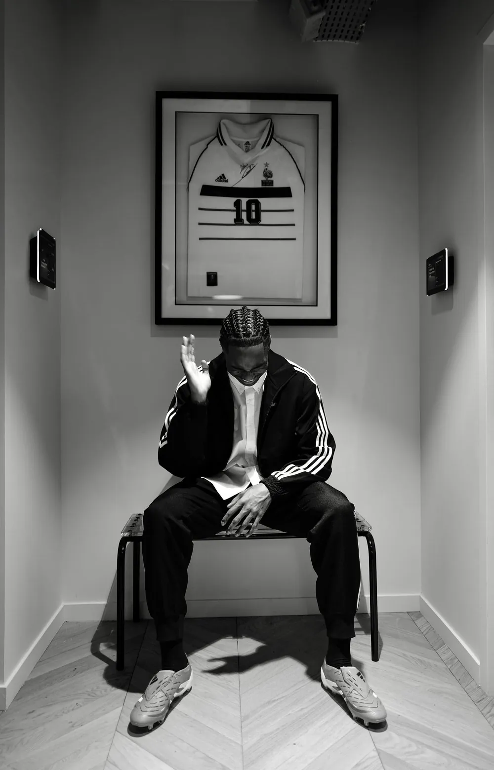 Mathys Tel en backstage du shooting adidas avec Colo Design Club, assis sous un maillot encadré